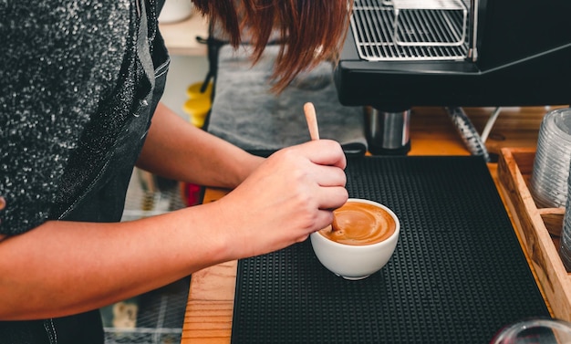 Barista che fa il caffè la mano di un barista con un cucchiaio di legno che fa o prepara la schiuma del caffè