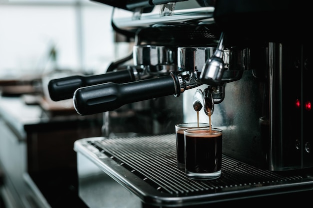 barista che mescola e versa il caffè nella tazza dalla macchina da caffè al bancone della piccola caffetteria