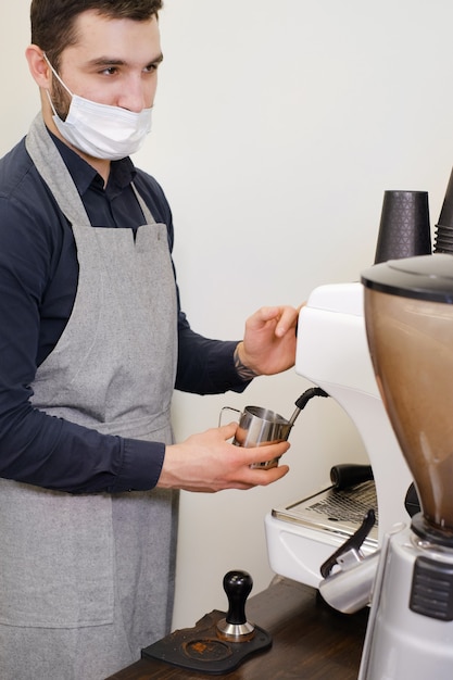 Barista che serve caffè in tazze da asporto in caffetteria in maschera