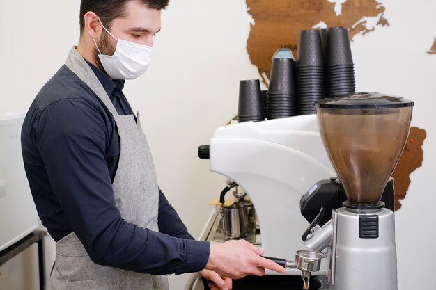 Barista che serve caffè in tazze da asporto nella caffetteria in maschera