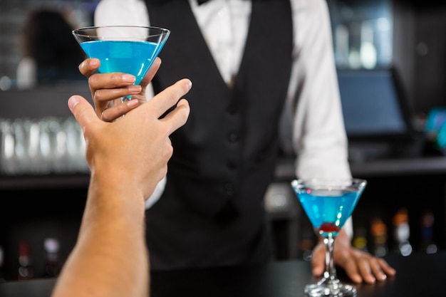 Barista che serve cocktail blu al bancone del bar nel bar