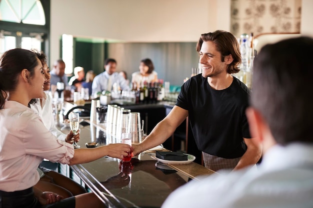 Barista che serve due imprenditrici che si incontrano per un drink dopo il lavoro