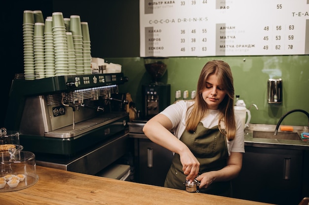 Barista che tempera il caffè macinato nella caraffa per espresso