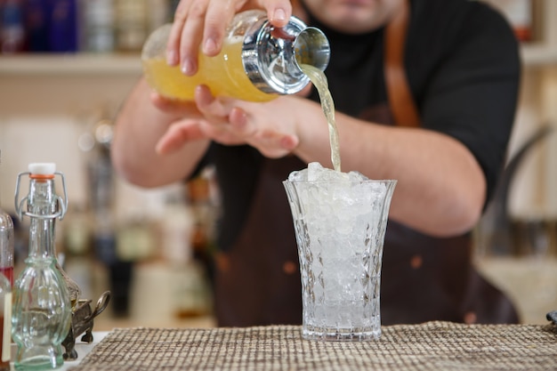 Barista che versa cocktail nel bicchiere al bar