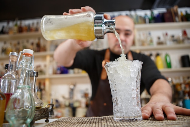 Barista che versa cocktail nel bicchiere al bar