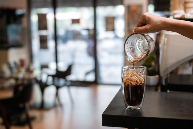 Barista che versa il latte in un bicchiere di caffè freddo