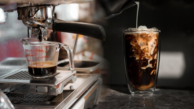 Barista che versa il latte in un bicchiere di caffè freddo