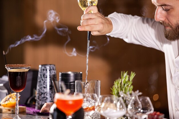 Barista che versa ingredienti per cocktail. Atmosfera lounge