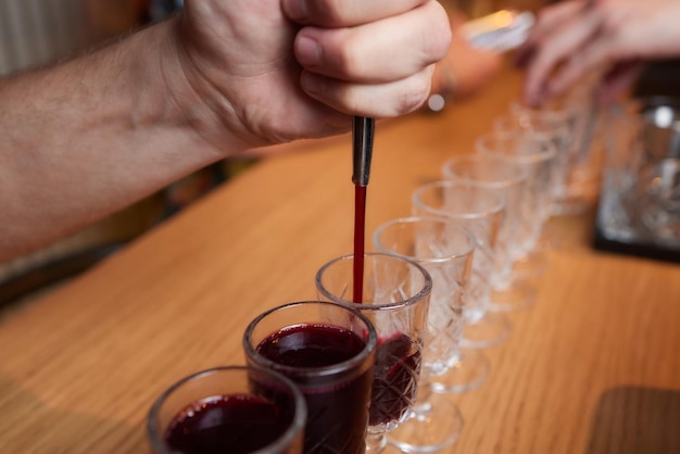 Barista che versa una forte bevanda alcolica in piccoli bicchieri sugli scatti del bar