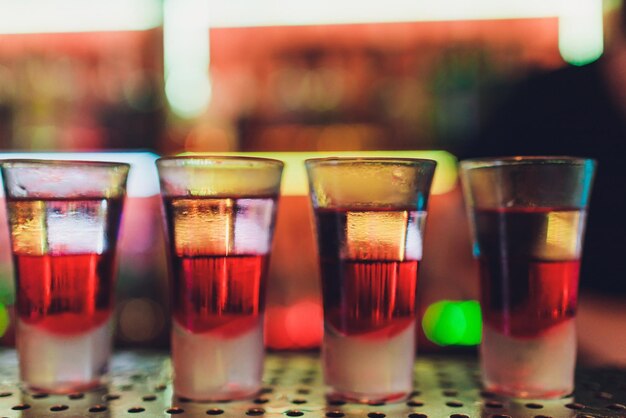 Barista che versa una forte bevanda alcolica in piccoli bicchieri sugli scatti del bar