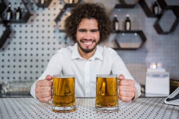Barista con due bicchieri di birra nel bancone del bar