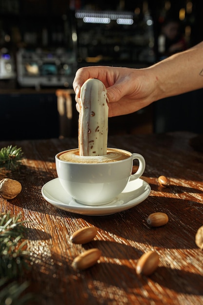 barista con eclair alla crema e tazza di gustoso cappuccino al tavolo di legno