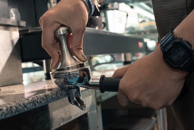 Barista con portafiltro e manomissione del caffè mentre prepara un caffè espresso