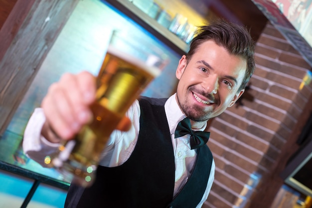 Barista di smiley bello che allunga le tazze di birra.