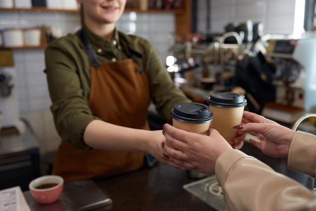 Barista donna che serve caffè in tazze di carta da asporto