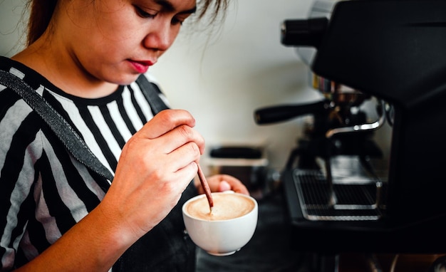 Barista donna nella caffetteria che si prepara a cuocere a vapore il latte per una tazza di caffè menu cappuccino