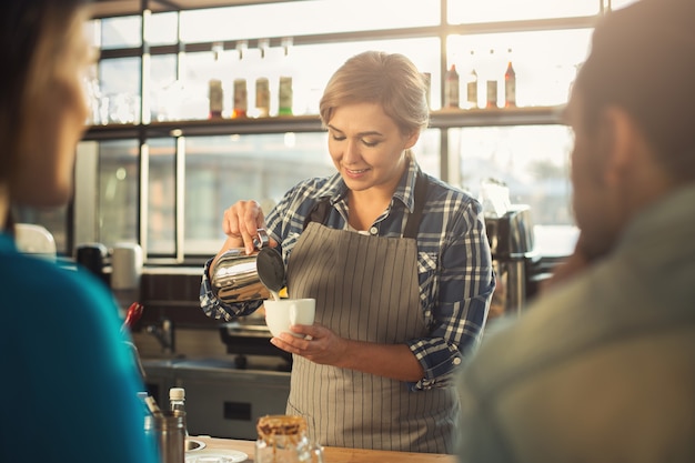 Barista esperto in uniforme che prepara caffè per coppia. Piccole imprese, persone di occupazione e concetto di servizio, spazio di copia