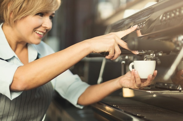 Barista esperto nella preparazione del caffè in una macchina da caffè professionale. Donna che prepara bevanda. Concentrati sulle mani. Piccola impresa e concetto di preparazione del caffè professionale