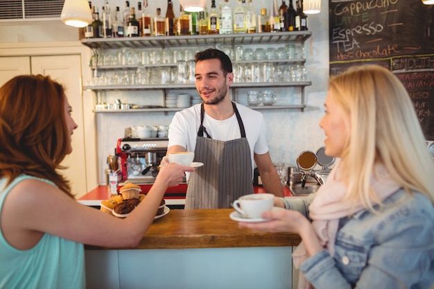 Barista felice che serve caffè al cliente femminile al caffè