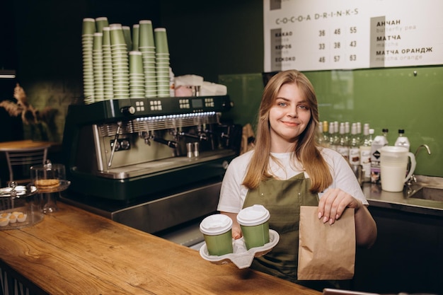 Barista femminile che dà caffè in tazze di cartone