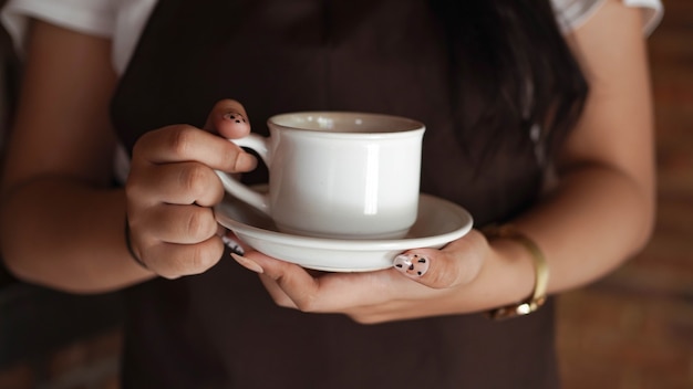 Barista femminile che tiene tazza di caffè al caffè