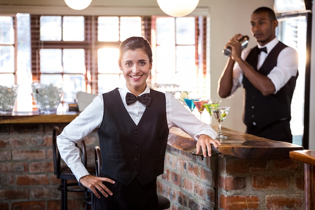 Barista femminile sorridente che sta al contatore della barra