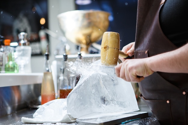 Barista ghiaccio tritato manualmente con martello di legno e coltello di metallo.