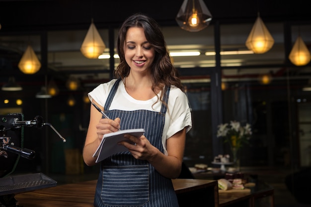 Barista grazioso che prende appunti