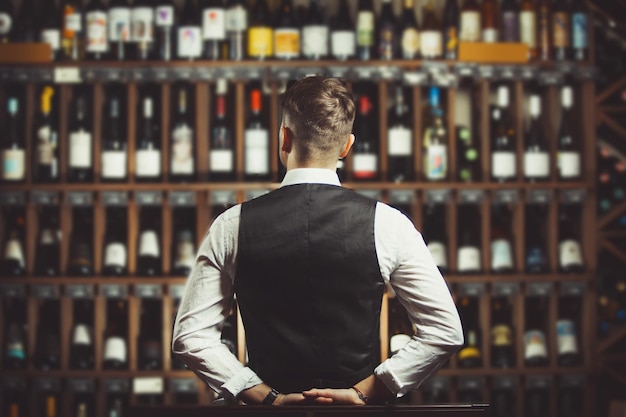 Barista in cantina piena di bottiglie con squisite bevande