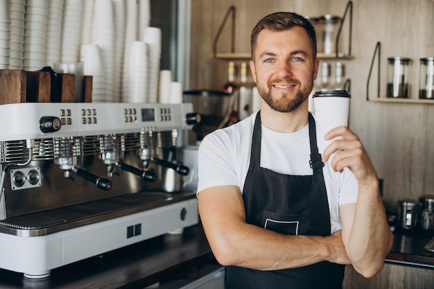 Barista maschio che tiene il caffè in una tazza di cartone