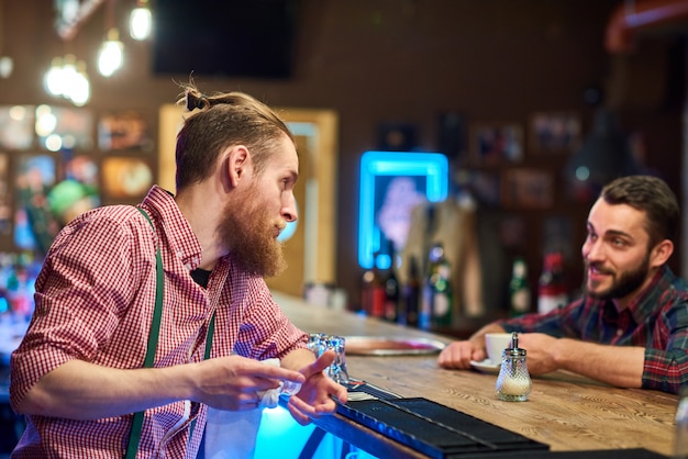 Barista parlando al visitatore al bancone del pub