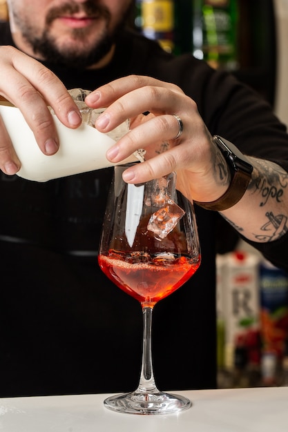 Barista prepara sul bancone Aperol Spritz un classico rinfrescante aperitivo italiano fatto miscelando