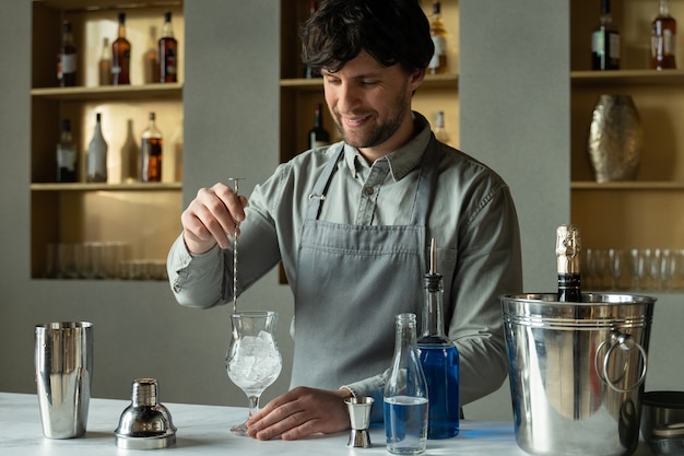 Barista professionista che mescola ghiaccio nel bicchiere sul bancone del bar