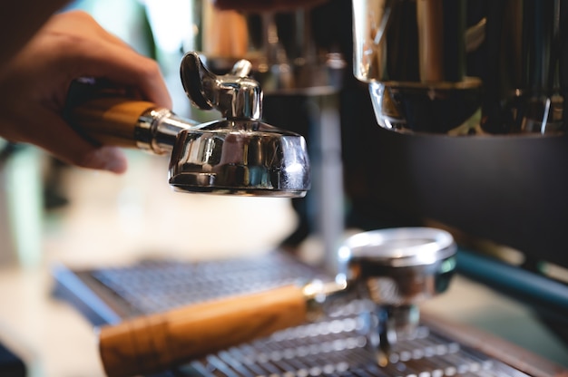 Barista professionista che prepara caffè espresso in una tazza da bere al bar, macchina per bevande caffeina, persona che versa acqua calda con la mano, colazione di lavoro al mattino, aroma fresco nella bevanda calda