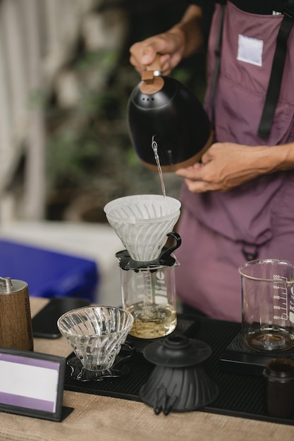 Barista professionista che prepara il caffè usando chemex versa sulla caffettiera e sul bollitore