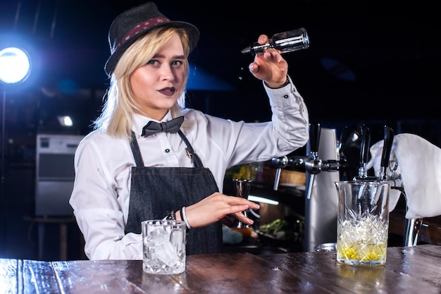 Barista professionista termina intensamente la sua creazione mentre si trova vicino al bancone del bar in discoteca