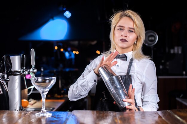 Barista ragazza graziosa che versa bevanda alcolica fresca nei bicchieri nei cocktail bar