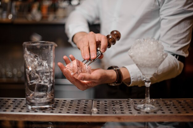 Barista rompendo un cubetto di ghiaccio per il cocktail