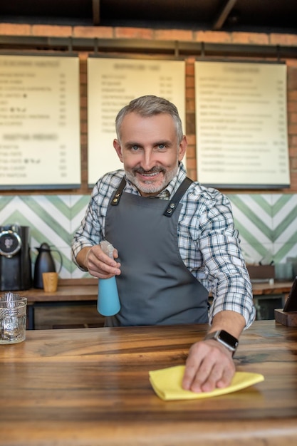 Barista soddisfatto sorridente che pulisce il controsoffitto di legno