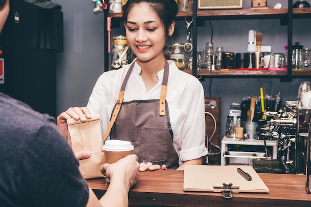 Barista sorridente che dà il caffè al cliente al caffè