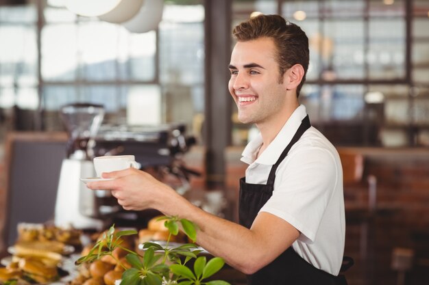 Barista sorridente che offre tazza di caffè