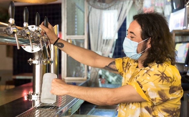 Barista tatuato che versa una brocca di birra.