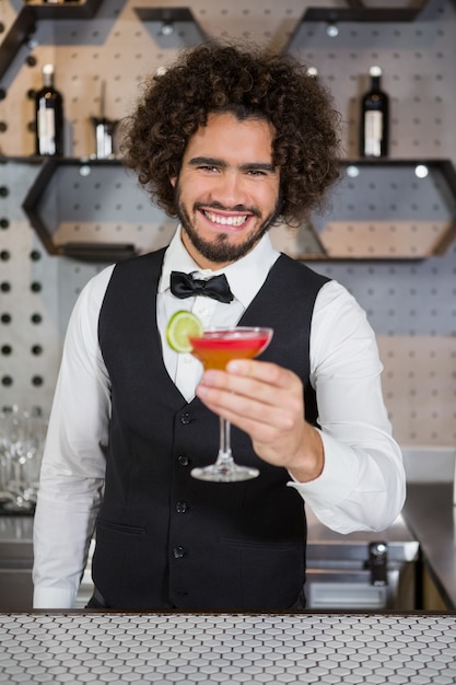 Barista tenendo il bicchiere di cocktail nel bancone bar