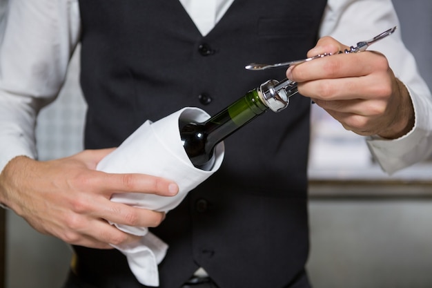 Barista usando il cavatappi per aprire la bottiglia di vino