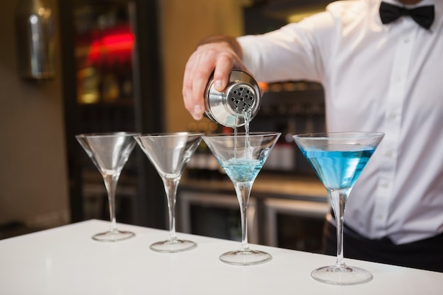 Barista versando alcol blu nel bicchiere da cocktail