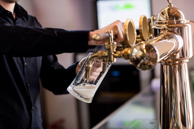 Barista versando birra dal rubinetto nel bicchiere di pinta