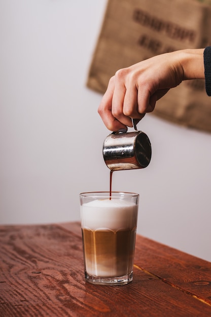 Barista versando il latte nel caffè cappuccino in coffeeshop