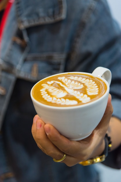 Barista versando la schiuma di latte per fare un caffè latte art nella tazza di caffè bianco