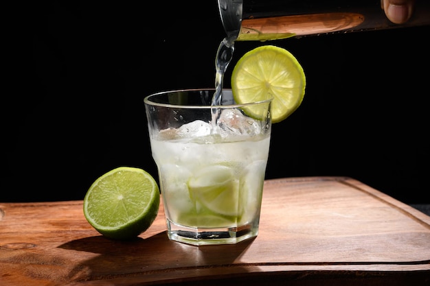 barista039s mano versando un drink in un bicchiere con limone e ghiaccio per un drink su uno sfondo nero
