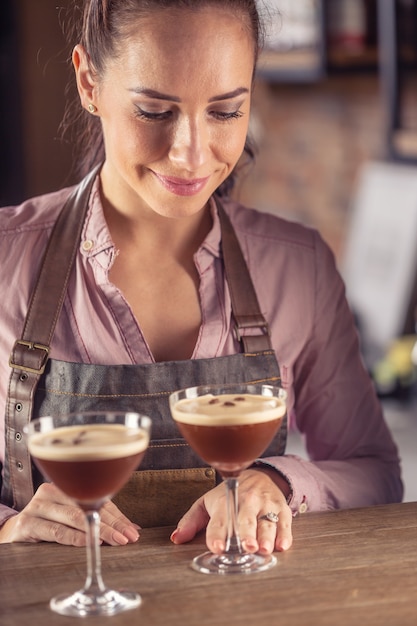 Barmaid serve due cocktail di caffè espresso martini in un bar.